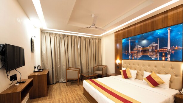 Ein Hotelzimmer mit einem großen Bett, einem Flachbildfernseher, einem Schreibtisch und einem Stuhl.