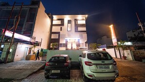 Ein Hotel mit moderner Fassade, einem gut beleuchteten Eingang und zwei vor der Tür stehenden Autos.