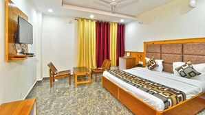 Une chambre d’hôtel équipée d’un lit, d’un bureau, d’une chaise, d’une télévision et d’un ventilateur de plafond.