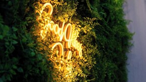 A neon sign reading "Happy New Year" amidst lush greenery.