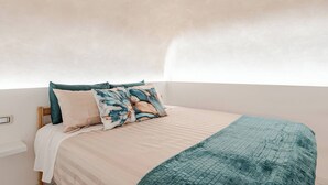 A bedroom with a bed, pillows, and a blanket.