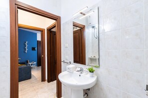 A modern bathroom with a white sink, a mirror, and a shower. - Casa Mimi (Alghero)