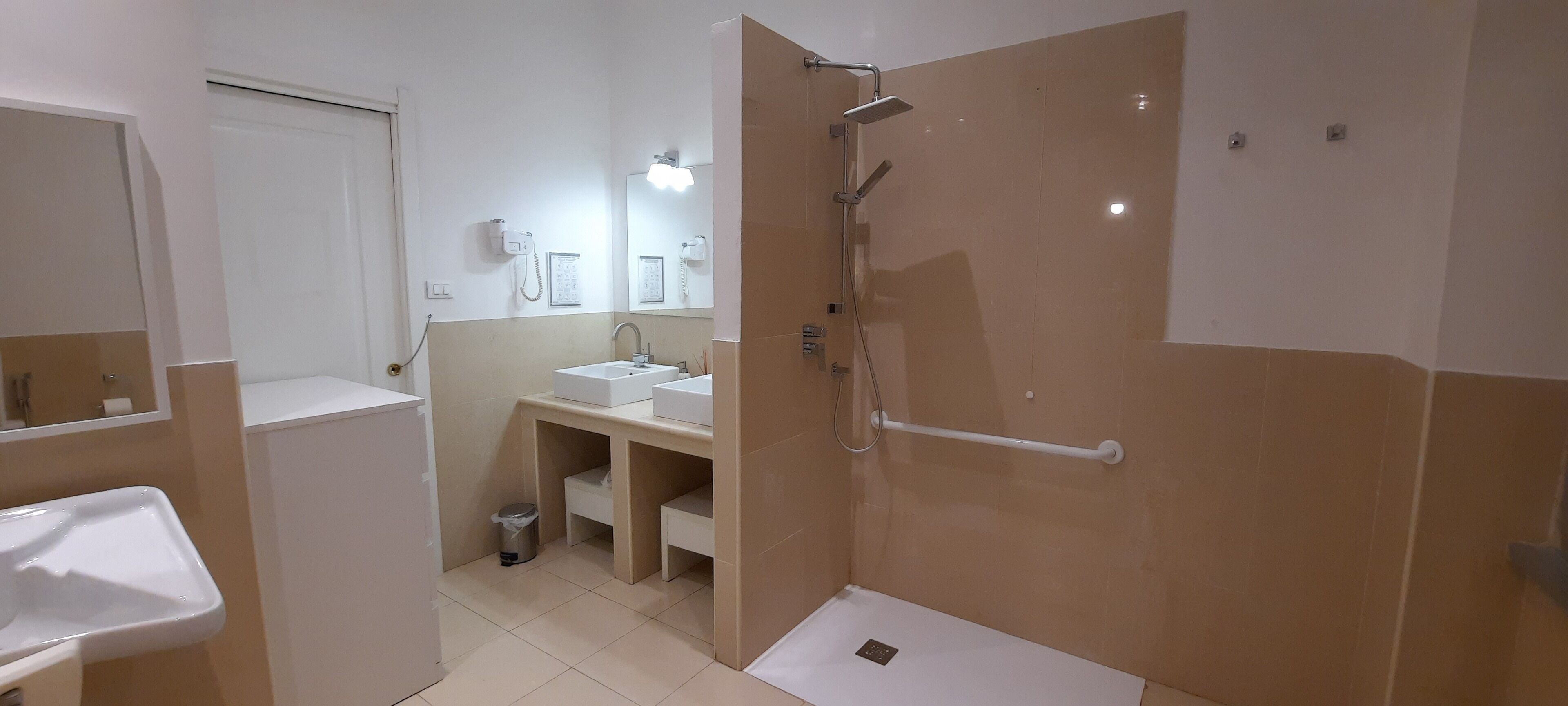 Ein modernes Badezimmer mit Dusche, zwei Waschbecken, einem Spiegel und einer Toilette.