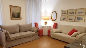 A living room with two sofas, a small table with a lamp, and framed pictures on the wall. - Rooms Palazzo Groppallo  (Genoa)