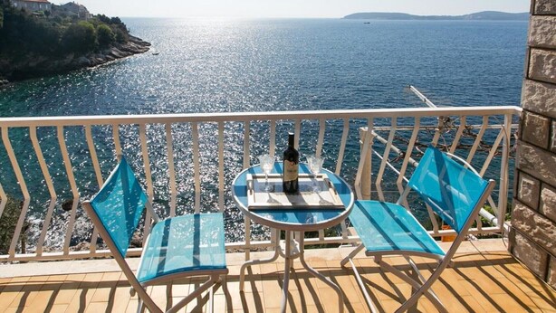 A balcony with a table and chairs overlooking a body of water. - Apartments Neve - One-Bedroom Apartment with Balcony and Sea View (Zaton)