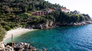 A coastal area with a beach, clear blue waters, and buildings on a hillside. - Apartments Neve - One-Bedroom Apartment with Balcony and Sea View (Zaton)