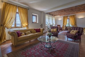 Un soggiorno con un divano beige, due poltrone, un tavolino in vetro e tappeti decorati.