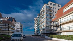 Un immeuble résidentiel à plusieurs étages, doté de balcons, avec un ciel dégagé.