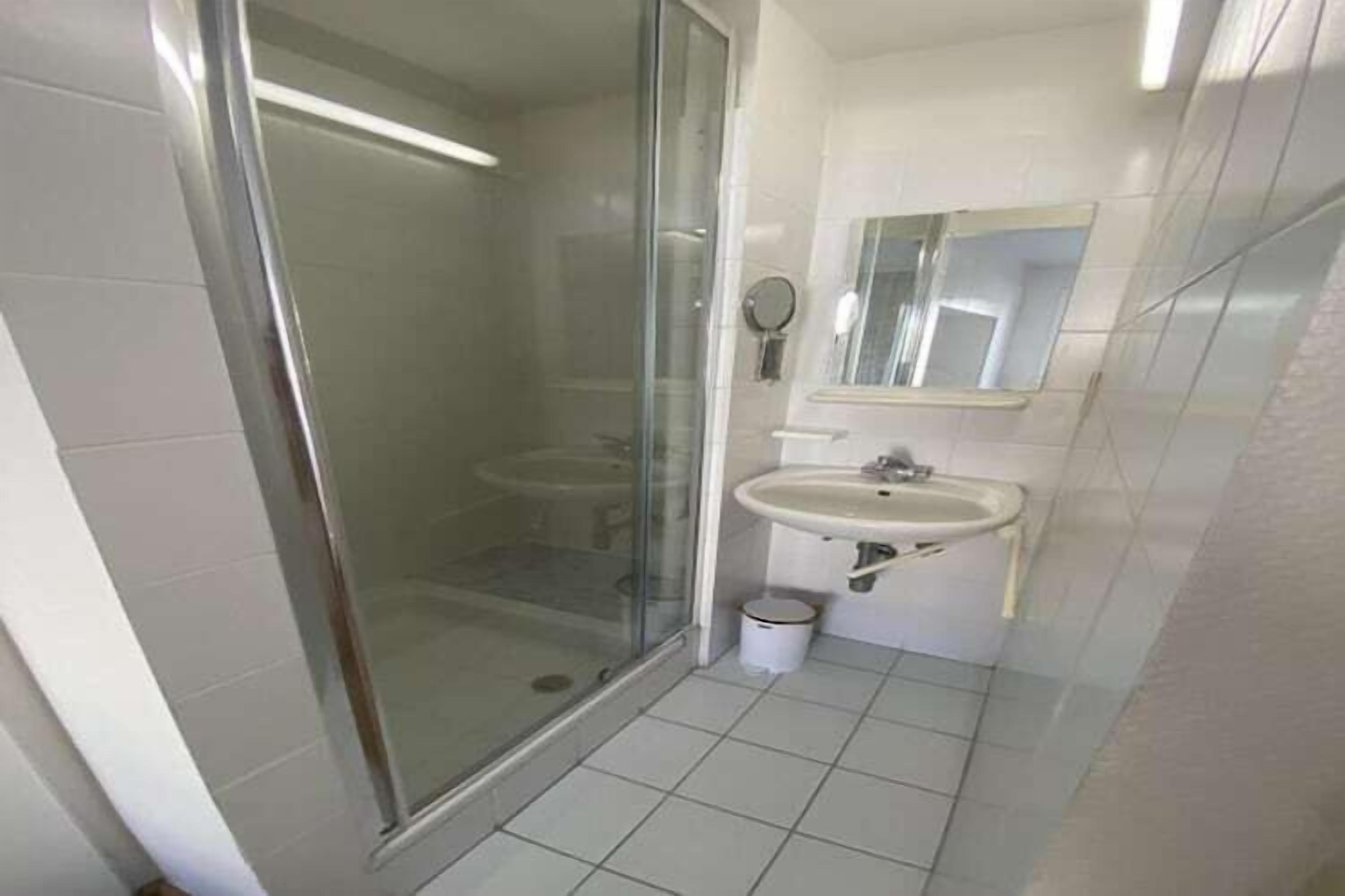 Une salle de bain avec une douche à parois de verre, un lavabo et un miroir.