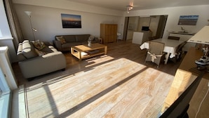 Een moderne woonkamer met een bank, salontafel en eethoek.
