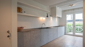 A modern kitchen with a built-in sink, a wooden shelf, and a large sliding glass door leading to a balcony.