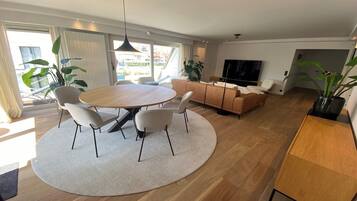 Een moderne woonkamer met een ronde eettafel, banken en een televisie.