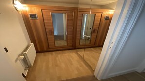 A hallway with wooden paneling, a radiator, and a mirror on the wall. - Duplex in Knokke-Heist near Beach & Casino (KNOKKE-HEIST)