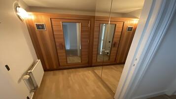 Een gang met houten lambrisering, een radiator en een spiegel aan de muur.
