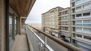 Een balkon met uitzicht op een strand en omliggende gebouwen.