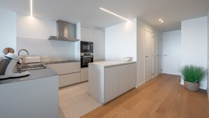 A modern kitchen with white cabinetry, a built-in oven, and a coffee machine. - Apartment in Knokke with Sea View (KNOKKE-HEIST)