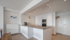 Una cocina moderna con armarios blancos, una isla central y electrodomésticos integrados.