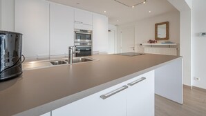 Una cocina moderna con muebles blancos, electrodomésticos de acero inoxidable y encimera marrón.