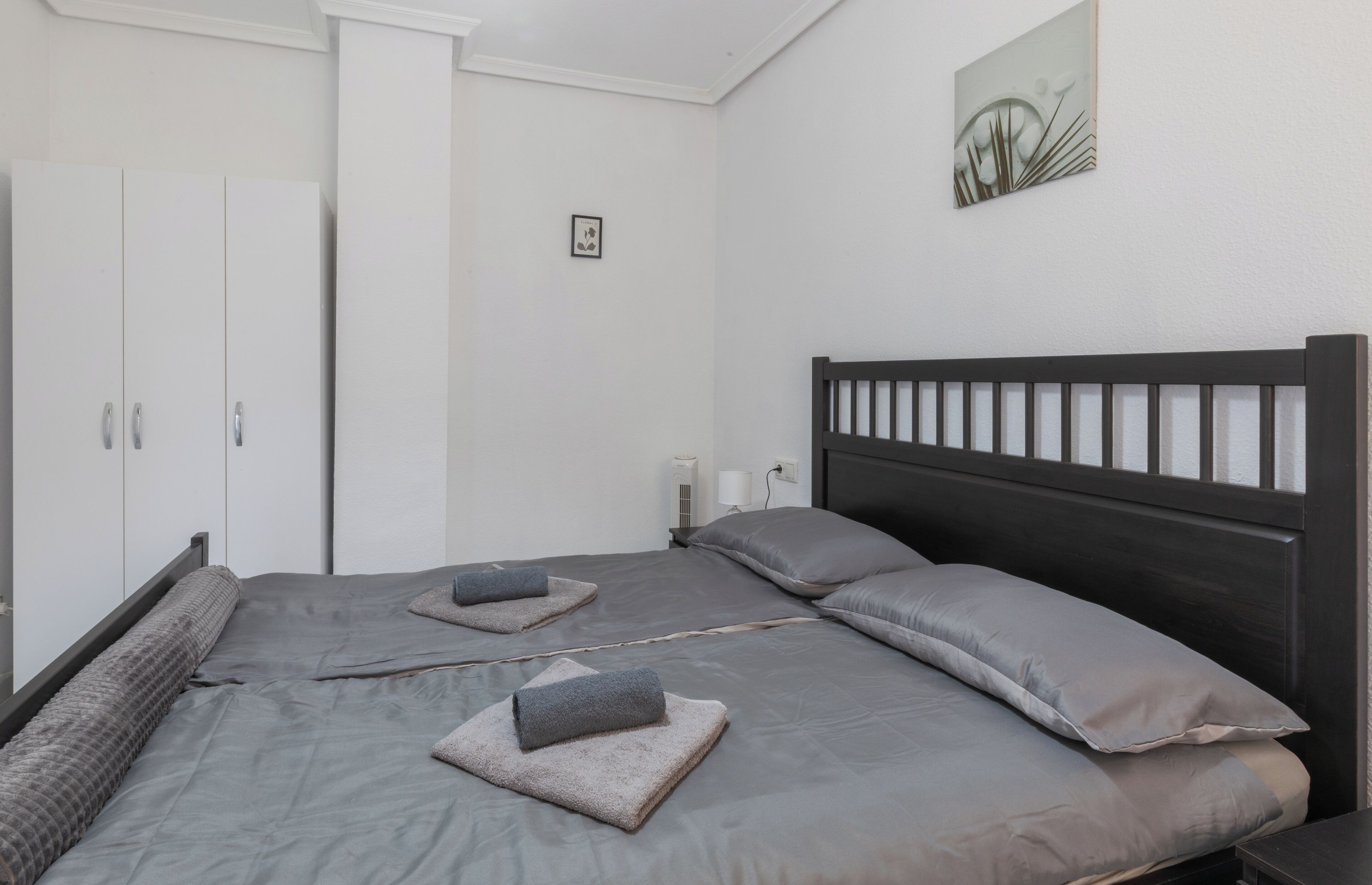 A bedroom with a large bed, two pillows, a headboard, and a wardrobe.
