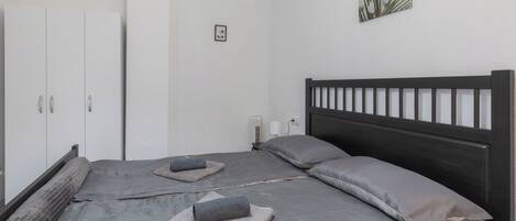 A bedroom with a large bed, two pillows, a headboard, and a wardrobe.