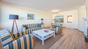 A living room with striped sofas, a white coffee table, and paintings on the walls. - Apartment in Knokke near Casino and Beach (KNOKKE-HEIST)