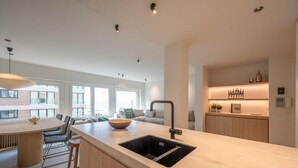 A modern kitchen with a large island, bar stools, and a built-in sink.
