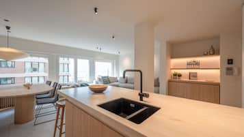 Een moderne keuken met een groot schiereiland, barkrukken en een ingebouwde gootsteen.