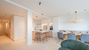 A modern kitchen with a central island, bar stools, and a dining area with chairs.