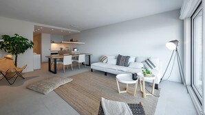 A modern living room with a sofa, coffee table, and dining area.