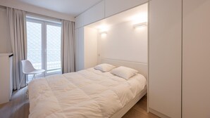 Une chambre moderne avec un grand lit, une chaise et une armoire.