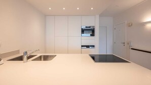 Une cuisine moderne dotée de deux éviers, d’appareils électroménagers en acier inoxydable et d’un éclairage encastré au plafond.