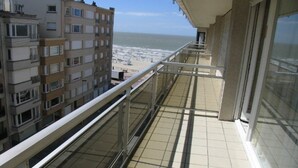 Un balcon donnant sur une plage et les bâtiments avoisinants.