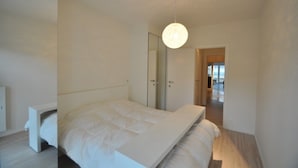 Une chambre à coucher moderne avec un lit, une armoire et un luminaire suspendu.