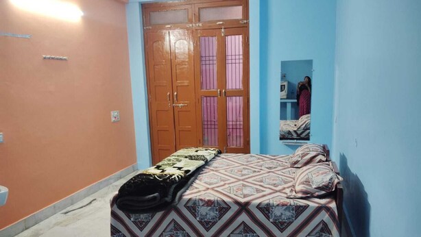A bedroom with a bed, a wardrobe, and a mirror. - Ramakantam Home Stay (Faizabad)