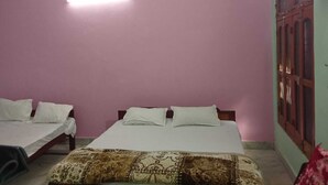 A room with two single beds, a patterned blanket, a ceiling fan, and an air conditioning unit. - Ramakantam Home Stay (Faizabad)