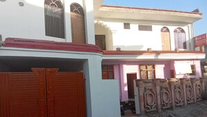 A two-story building with a red-tiled roof, a gated entrance, and a pink building adjacent to it. - Ramakantam Home Stay (Faizabad)