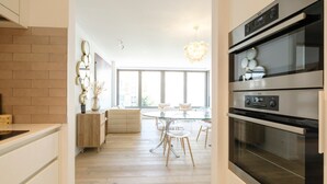 Eine moderne Küche mit einem großen Backofen, einem Essbereich mit einem Glastisch und Stühlen sowie einer Ziegelwand.