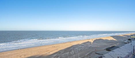 Vista de la playa con un paseo marítimo y cielo despejado.