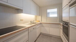 A modern kitchen with white cabinets, a black countertop, and stainless steel appliances.