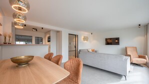 Un salon moderne avec un canapé, une table à manger et des chaises, ainsi qu’un grand miroir.