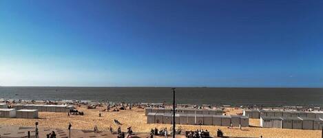 A beach with portable cabins and a parking area.