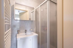 Een badkamer met een witte wastafel, een spiegel en een douchecabine.