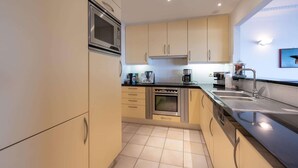 Una cucina moderna con elettrodomestici in acciaio inossidabile, mobili beige e un piano di lavoro nero.