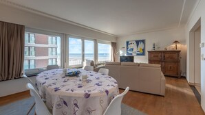 Un soggiorno moderno con un tavolo rotondo, una poltrona e un'ampia finestra vista mare.