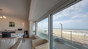 Sala de estar moderna com uma grande janela com vista para a praia e o aeroporto.