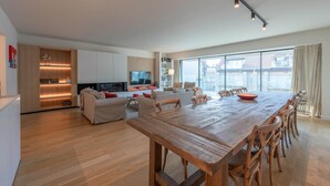 Ein geräumiger Wohnbereich mit Holztisch, Sofas und Fernseher.