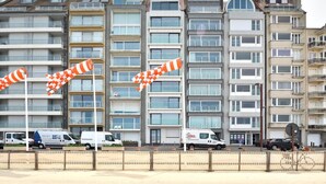 Un immeuble résidentiel à plusieurs étages, doté de balcons, d’une entrée sécurisée et d’une devanture de magasin bien visible.