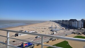 Vista de la playa con paseo marítimo, playa y edificios a lo largo de la costa.