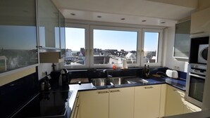 Una cocina moderna con ventanas amplias, horno empotrado y un lavamanos.