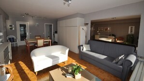 A living room with a sofa, a coffee table, and a dining area with a table and chairs. - Studio in Knokke-Heist near the Beach (KNOKKE-HEIST)